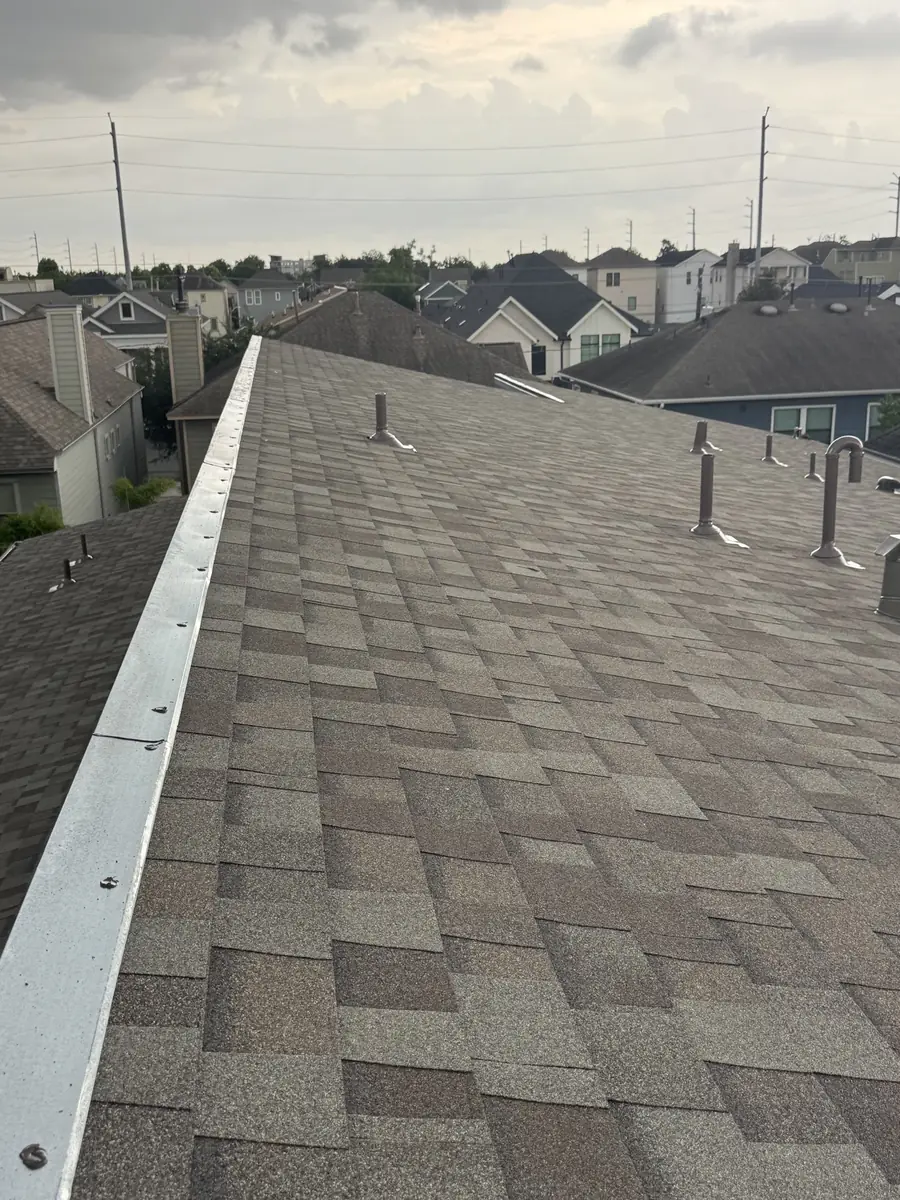 New ridge cap and tan architectural shingles along the main roofline, Houston TX