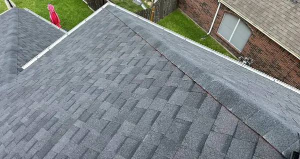 New roof and gutter line over the fenced side yard of a Houston home