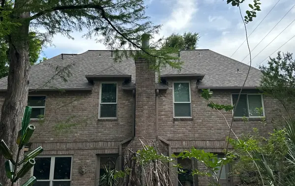 New roof over the rear elevation of a two-story brick house in Houston, TX