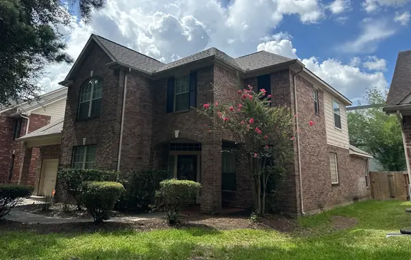Front of a two-story brick Houston home with a new Weathered Wood roof in 77040