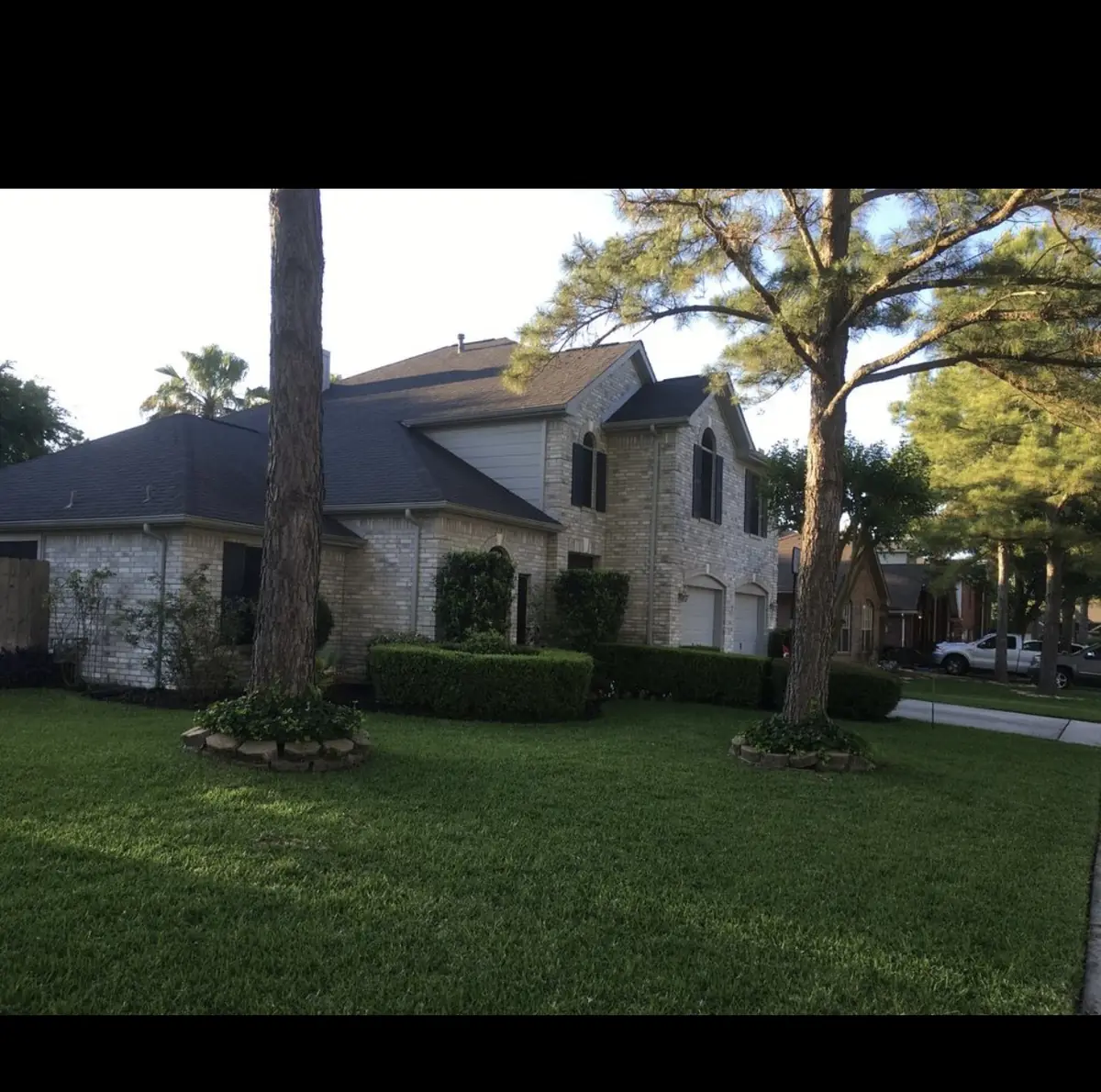 Front of a two-story Cypress home with the new gray roof under the pines