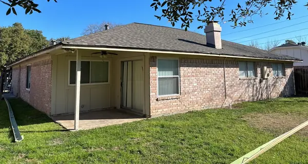 Rear of a one-story brick Katy home with a new tan-brown roof and patio