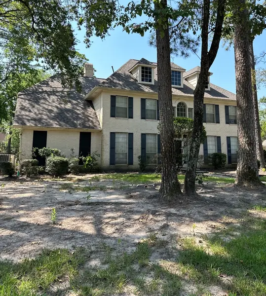 Front of a two-story Kingwood Colonial under pines with the new gray roof