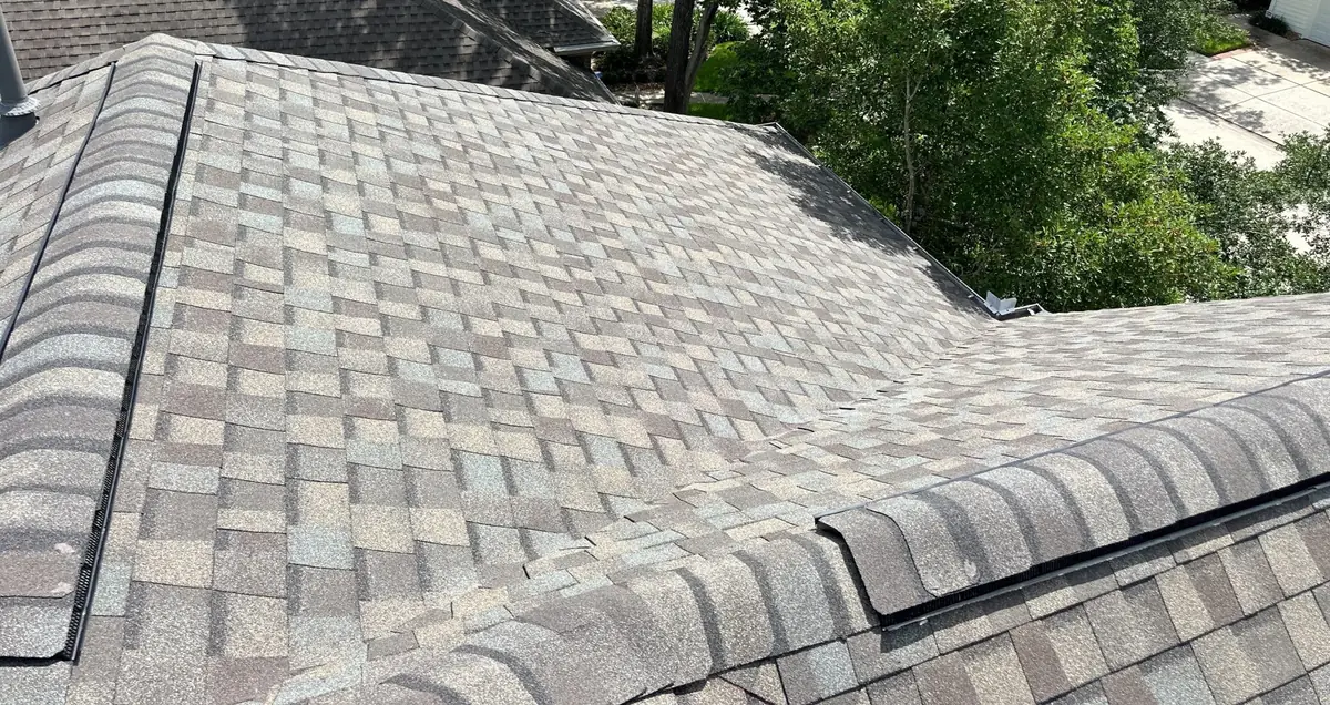 Hip and ridge caps of a new tan-brown roof in Cypress