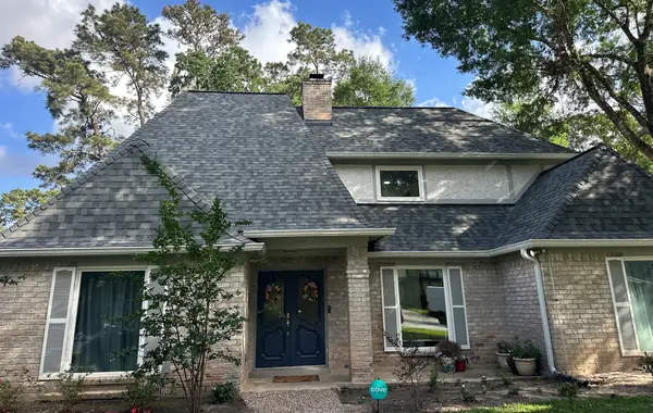 Front of a two-story brick Spring home with a new charcoal roof and dormer