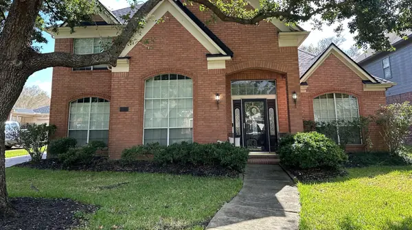 Front of a two-story brick Houston home with a new charcoal laminate roof in 77065