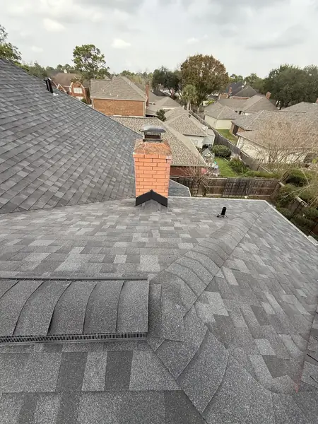 New pewter-gray roof and brick chimney on a two-story Houston home in 77095