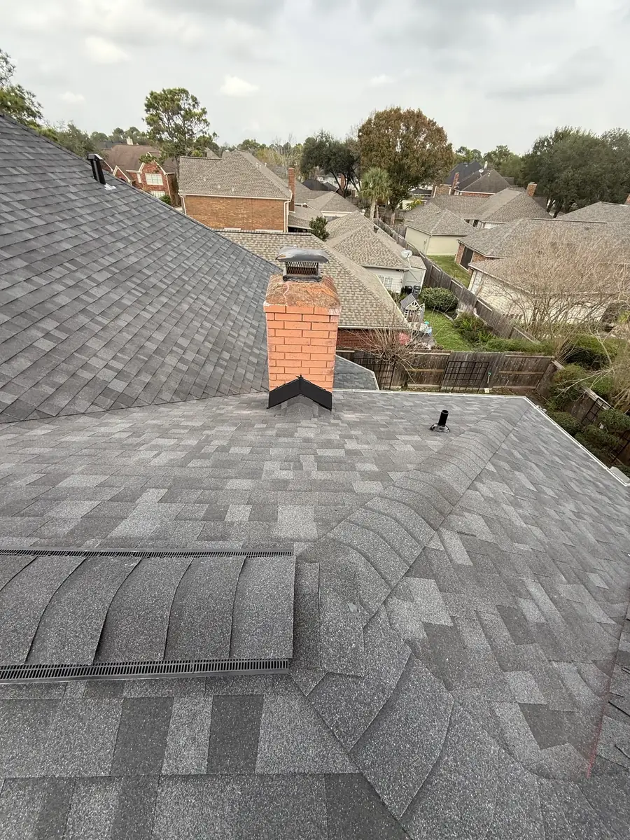 New pewter-gray roof and brick chimney on a two-story Houston home in 77095