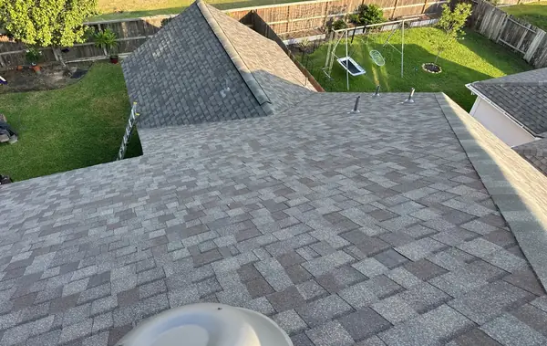 Hip of a new tan-brown roof in Tomball with a replaced dome vent